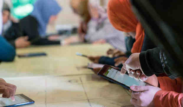 in Jordan, adolescent girls use cellphones and tablets in a solar kiosk providing internet connectivity in the Za’atari camp for Syrian refugees, near the Syrian border. Photo: UNICEF/Christopher Herwig