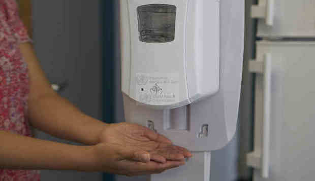 A health worker sanitizes her hands before putting on a mask. Photo: WHO