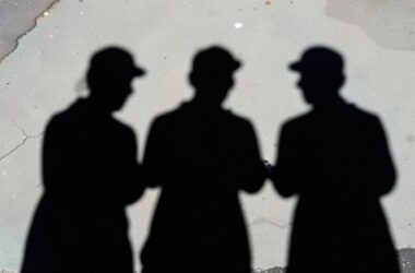 Shadows of anonymous individuals representing hidden digital threats and illicit ad markets.