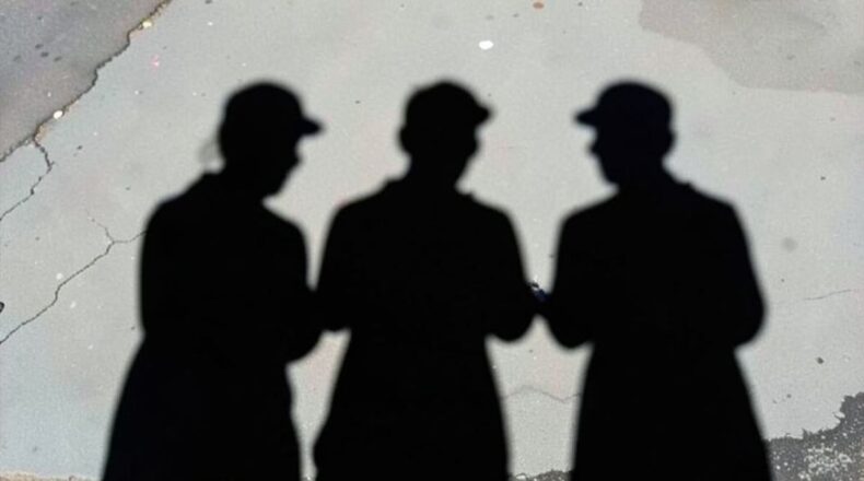 Shadows of anonymous individuals representing hidden digital threats and illicit ad markets.